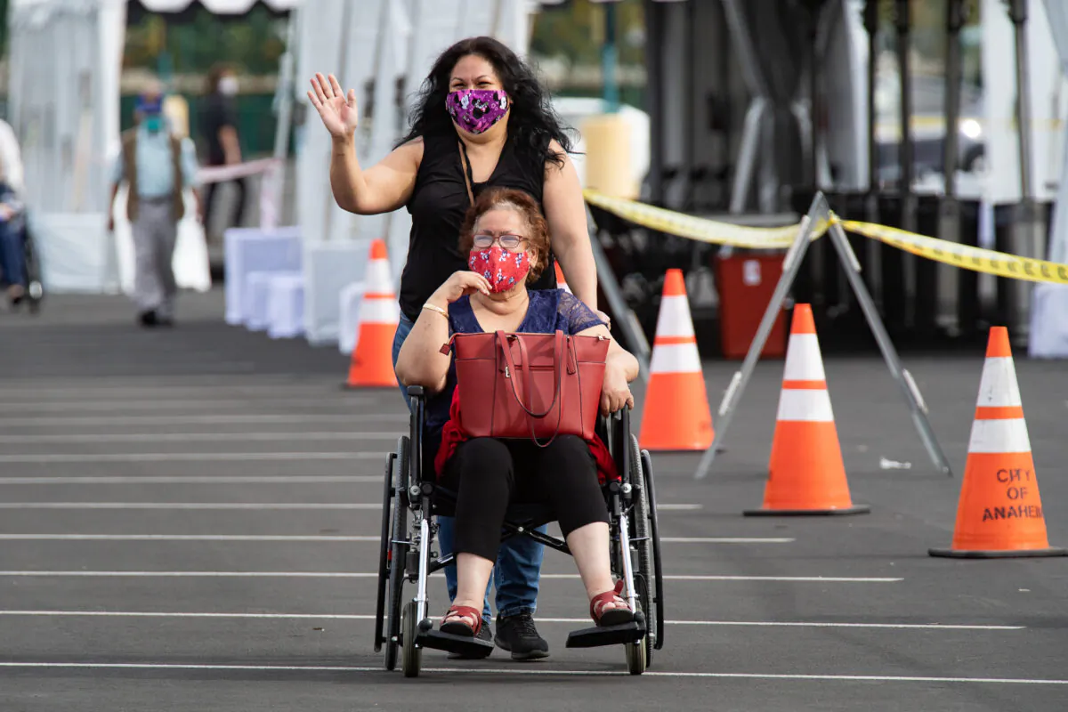 People wait to recieve a coronavirus vaccination at a point of distribution center in a parking area of Disneyland themepark in Anaheim, Calif., on Jan, 13, 2021. (John Fredricks/The Epoch Times)