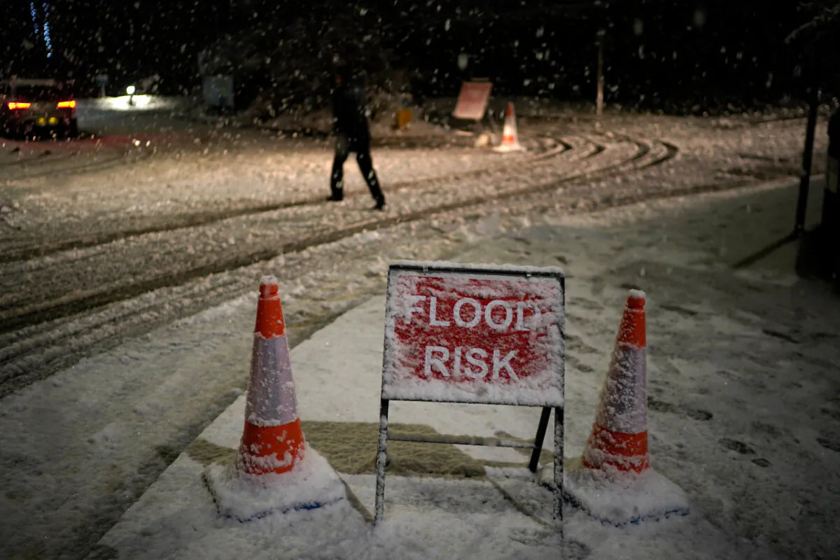 Danger to life flood warnings are given along the River Mersey in East Didsbury, West Didsbury and Northenden as Storm Christoph moves in on the UK. A person walks past a snow-covered flood warning sign in Didsbury, United Kingdom, on Jan. 20, 2021. (Christopher Furlong/Getty Images)