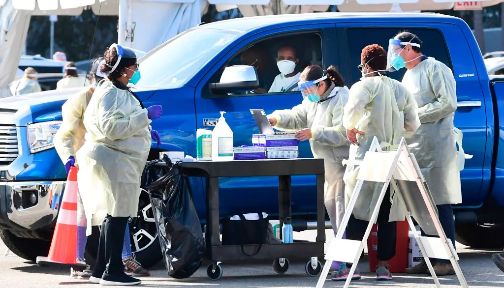 People pull up in their vehicles for COVID-19 vaccines in the parking lot of The Forum in Inglewood, California on January 19, 2021. 
(Frederic J. Brown BROWN/AFP via Getty Images)