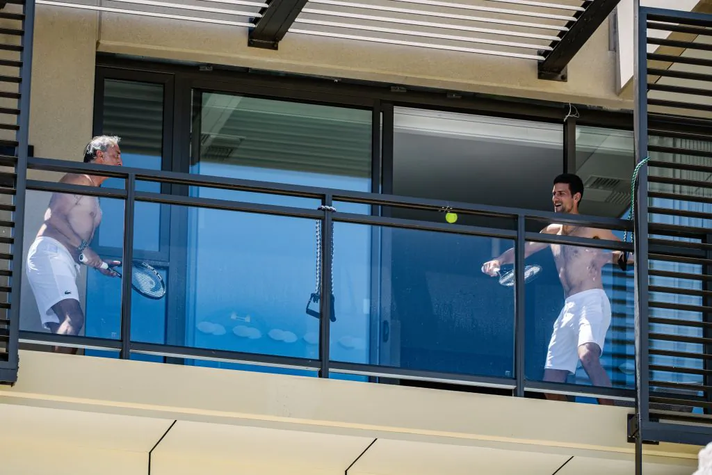 Support Staff (L) and Serbian World No.1 Tennis player Novak Djokovic (R) quarantined at the M Suites in North Adelaide in Adelaide, South Australia, January 20, 2021, ahead of the Australian Open Tennis Tournament. (Morgan Sette/AFP via Getty Images)