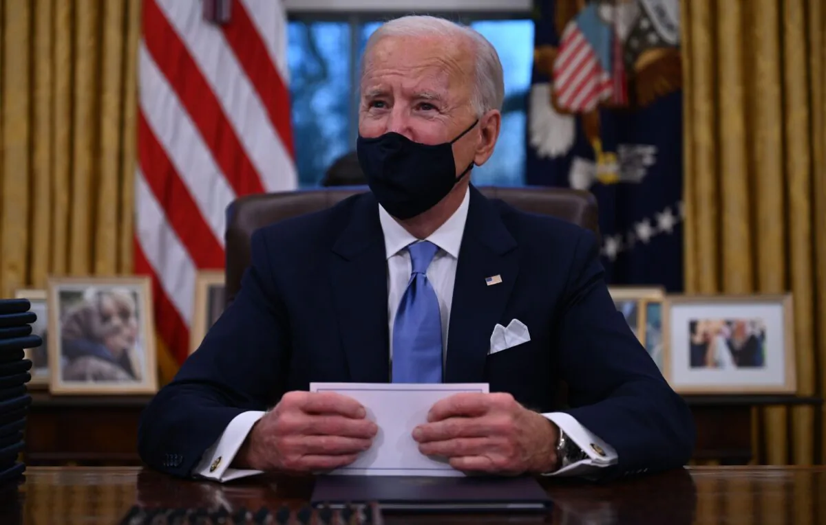 President Joe Biden prepares to sign a series of orders in the Oval Office of the White House in Washington on Jan. 20, 2021. (Jim Watson/AFP via Getty Images)