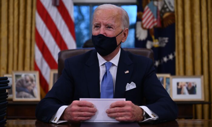 President Joe Biden prepares to sign a series of orders in the Oval Office of the White House in Washington on Jan. 20, 2021. (Jim Watson/AFP via Getty Images)