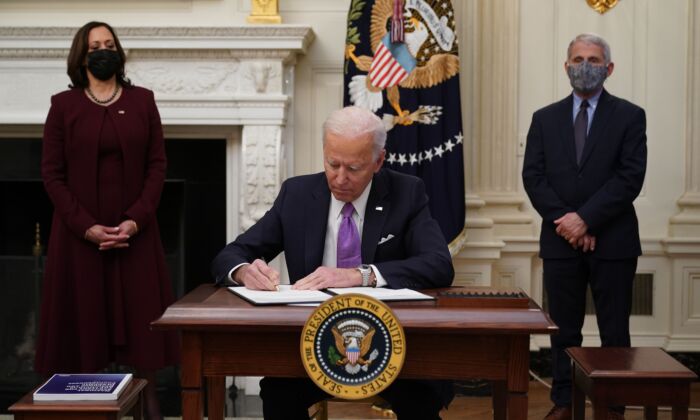 President Joe Biden signs executive orders as part of the COVID-19 response as Vice President Kamala Harris (L) and Director of NIAID Anthony Fauci look on in the State Dining Room of the White House, in Washington, on Jan. 21, 2021. (Mandel Ngan/AFP via Getty Images)