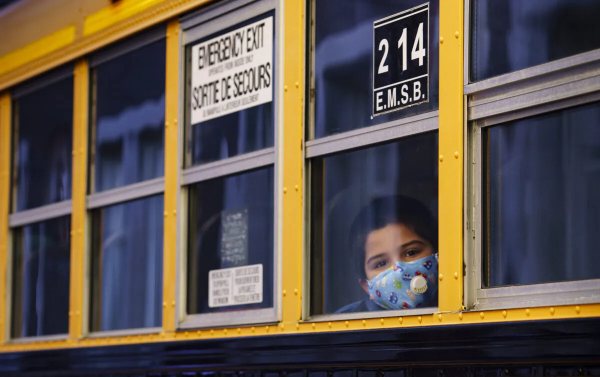 A student peers through the window of a school bus as he arrives at the Bancroft Elementary School in Montreal, Canada, on Aug. 31, 2020. (Paul Chiasson/The Canadian Press)