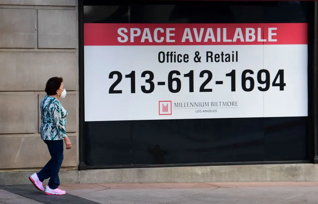 A woman walks past advertising for office and retail space available in downtown Los Angeles on May 4, 2020. (Fredric J. Brown/AFP via Getty Images)