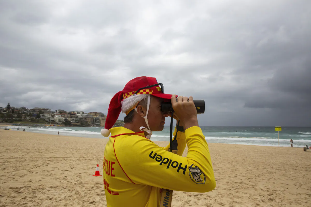 A surf rescue worker wearing a Santa hat looks through binoculars at Bondi Beach in Sydney, Australia on Dec. 25, 2020. (Jenny Evans/Getty Images)