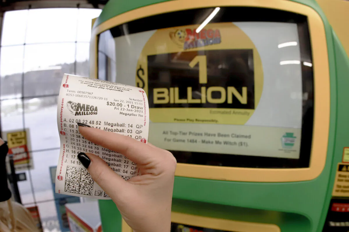 A patron, who did not want to give her name, shows the ticket she had just bought for the Mega Millions lottery drawing at the lottery ticket vending kiosk in a store in Cranberry Township, Pa., on Jan. 22, 2021. (Keith Srakocic/AP Photo)