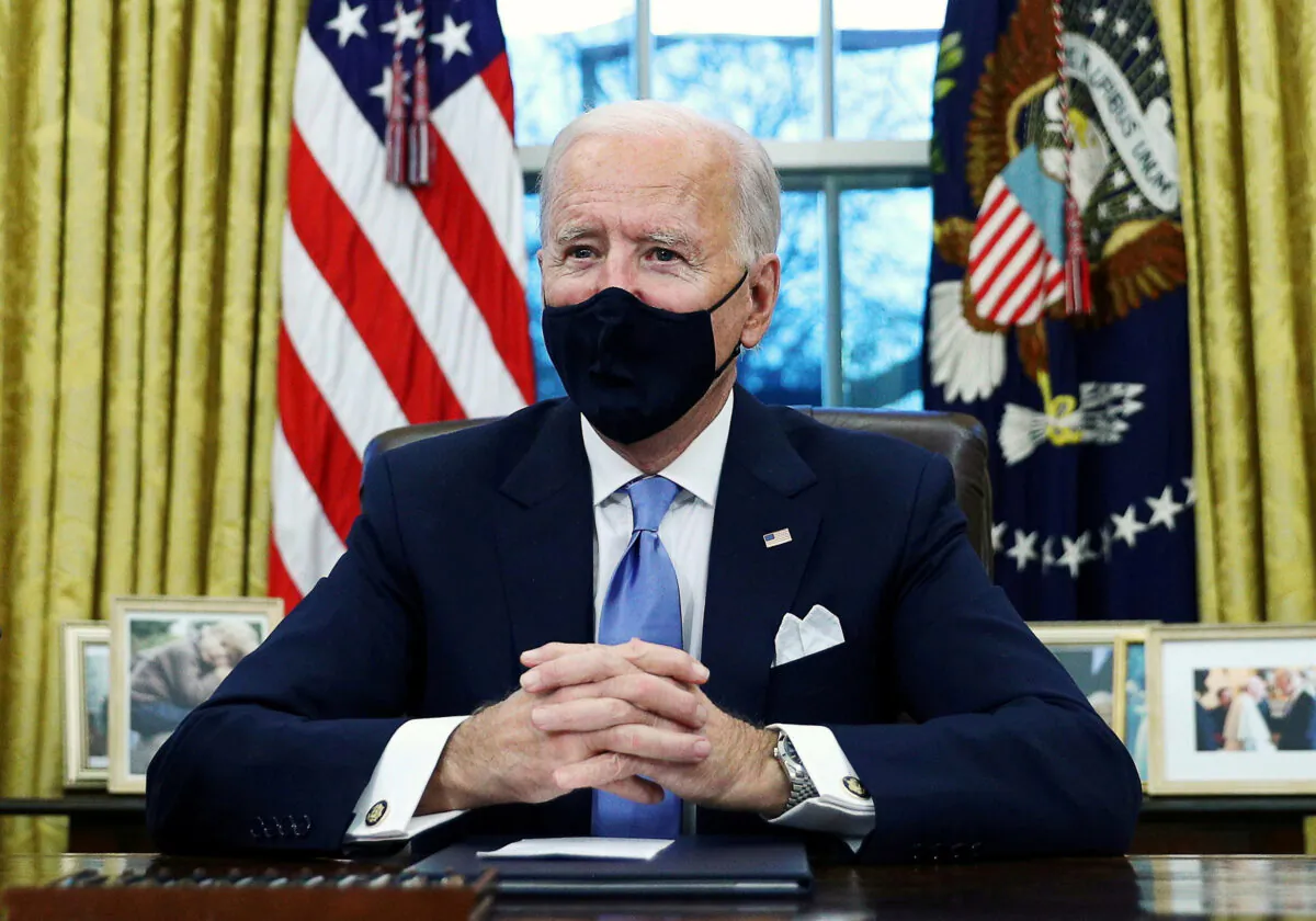 President Joe Biden signs executive orders in the Oval Office of the White House in Washington on Jan. 20, 2021. (Tom Brenner/Reuters)