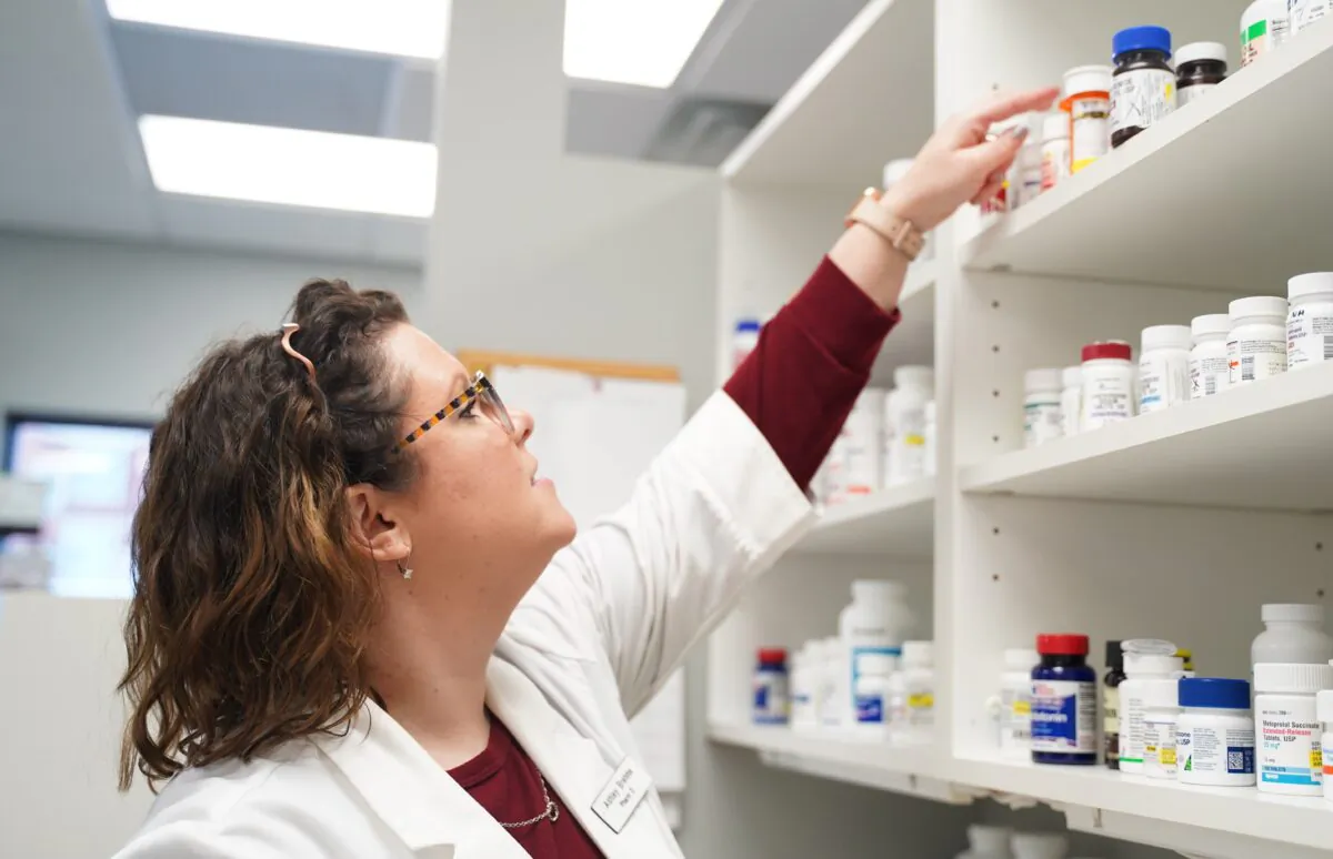 Pharmacist Ashley Brehme reaches for a pill bottle at the pharmacy she owns in Manchester, Iowa, on Jan. 16, 2021. (Cara Ding/The Epoch Times)