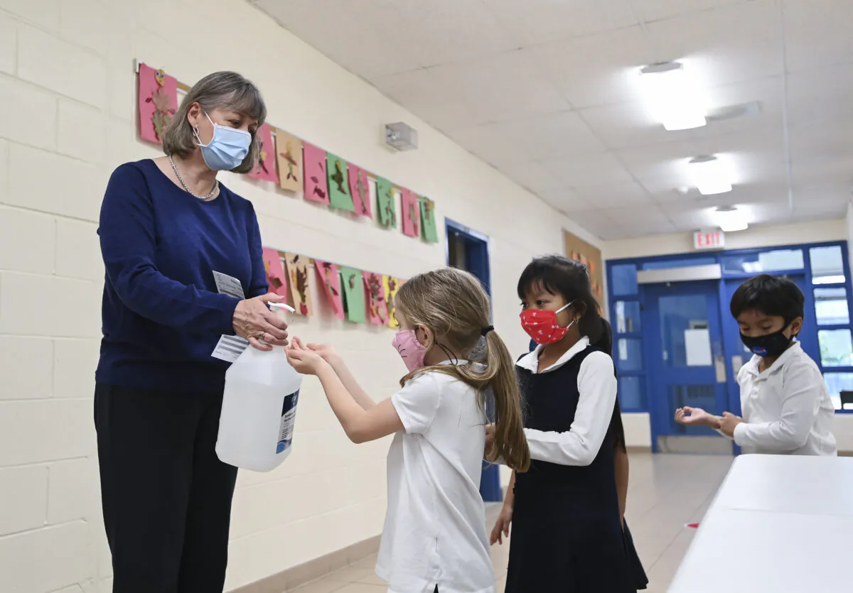 Children sanitize their hands while physical distancing after getting their pictures taken at picture day at St. Barnabas Catholic School during the COVID-19 pandemic in Scarborough, Ont., on Oct. 27, 2020. (The Canadian Press/Nathan Denette)