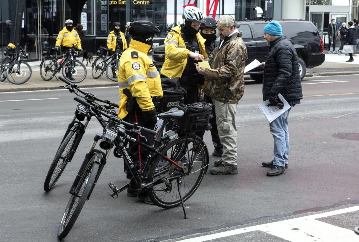 Police issue a summons to a protester after over 10 people gathered for an anti-lockdown rally against pandemic restrictions in Toronto on Dec. 19, 2020. (The Canadian Press/Chris Young) 