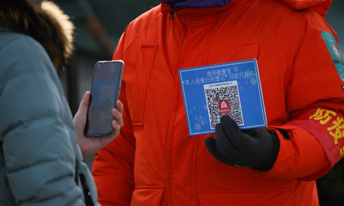 2021 年 1 月 12 日，一名妇女在进入中国北京的一个室外溜冰场之前，使用她的手机扫描场地代码进行健康登记。（Wang Zhao/AFP via Getty Images）