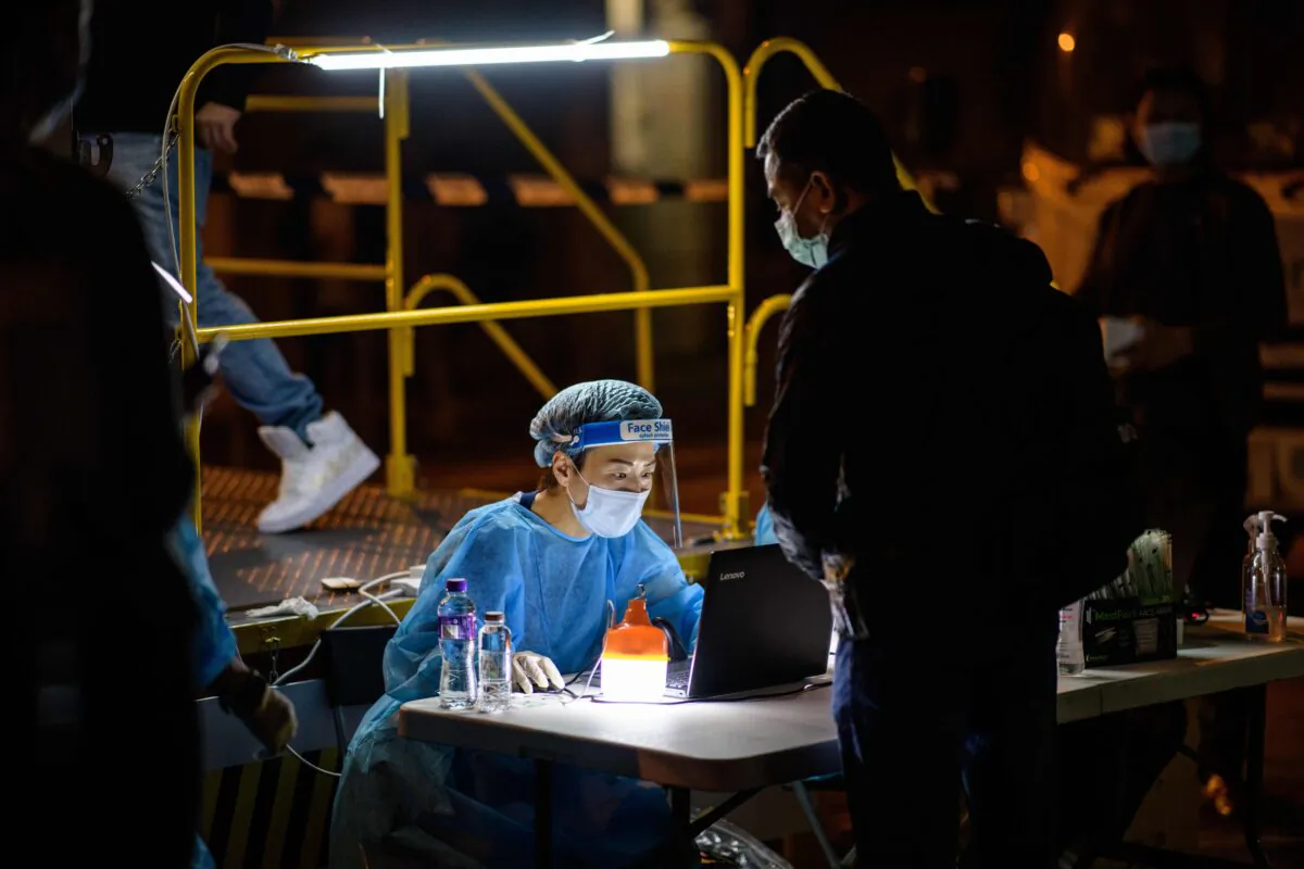 A resident registers for a mandatory COVID-19 test with a health worker wearing protective gear at a testing site in the Jordan area of the Yau Tsim Mong district of Kowloon in Hong Kong on Jan. 22, 2021. (ANTHONY WALLACE/AFP via Getty Images)