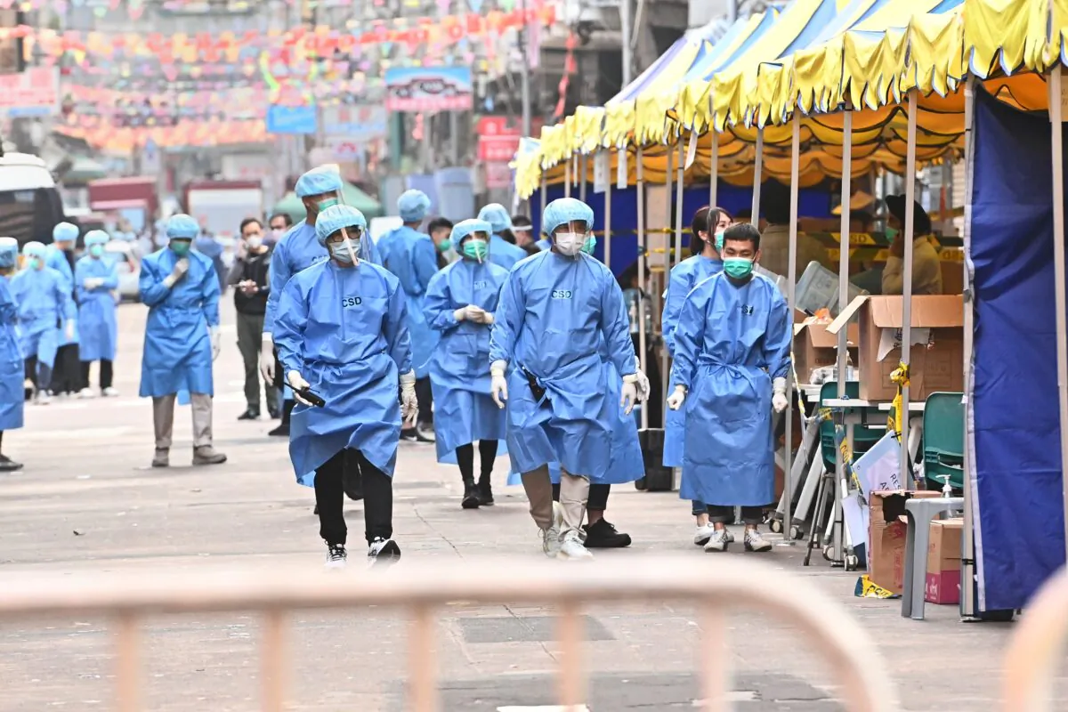 Medical workers walk on Temple Street in the lockdown area of Jordan in Hong Kong, on Jan. 24, 2021. The Hong Kong government recently enacted mainland-style lockdowns in its efforts to curb the spread of COVID-19. (Adrian Yu/Epoch Times)