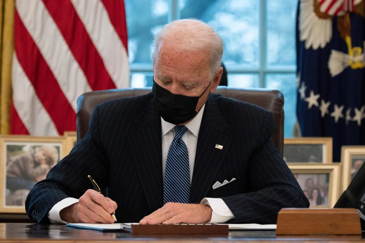 President Joe Biden signs an executive order reversing the Trump era ban on Transgender serving in the military, in the Oval Office of the White House on Jan. 25, 2021. (Jim Watson/AFP via Getty Images)