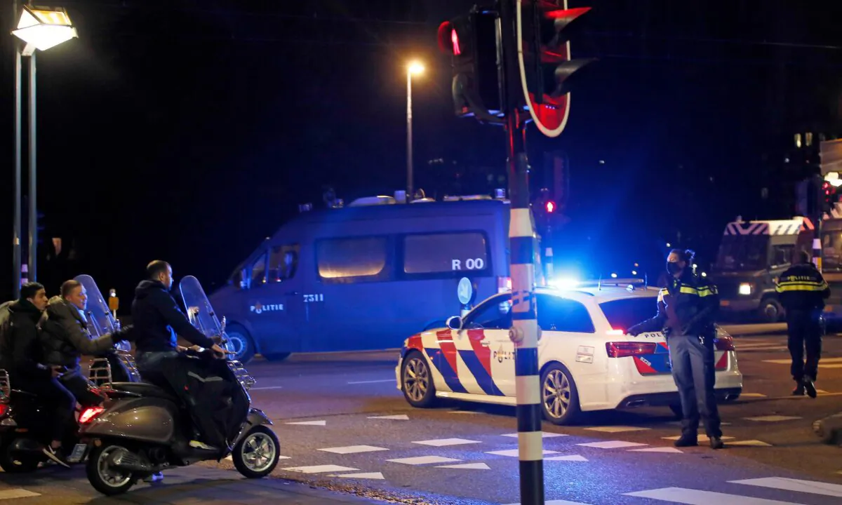 A police officer speaks to youths on scooters at a road block during a nation-wide curfew in Amsterdam, Netherlands, on Jan. 26, 2021. (Peter Dejong/AP Photo)