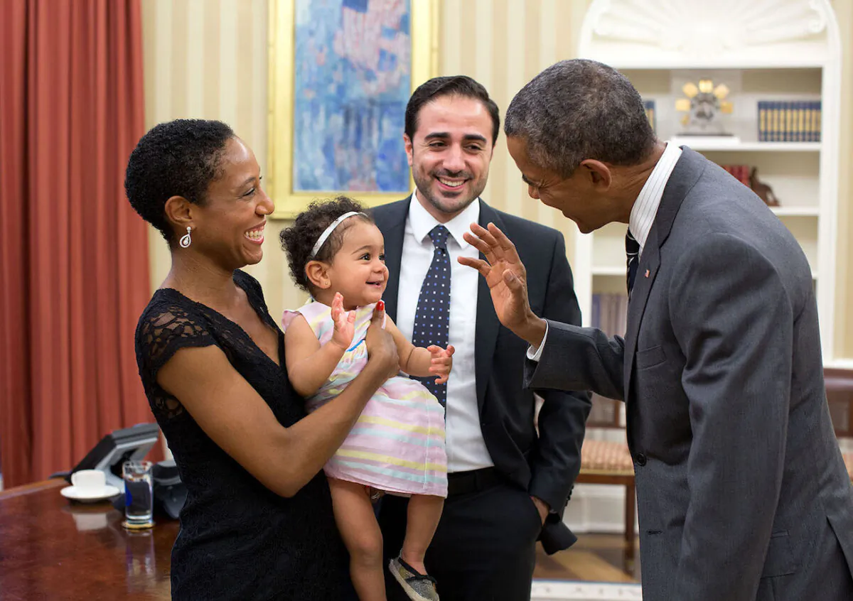 President Barack Obama greets Alya Dorelien Bitar, the 1-year-old daughter of Maher Bitar, the outgoing National Security Council Director for Israeli and Palestinian Affairs, and his wife, Astrid Dorelien, during a family photo in the Oval Office, on Sept. 21, 2015. (White House/Pete Souza)