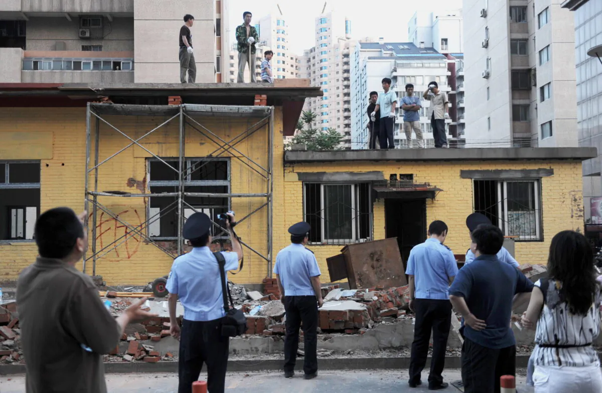 Chinese police film workers demolishing a group of buildings. Local residents claim the land belonged to their community and was were illegally built upon by a property company, in Beijing on May 31, 2010. (STR/AFP via Getty Images)