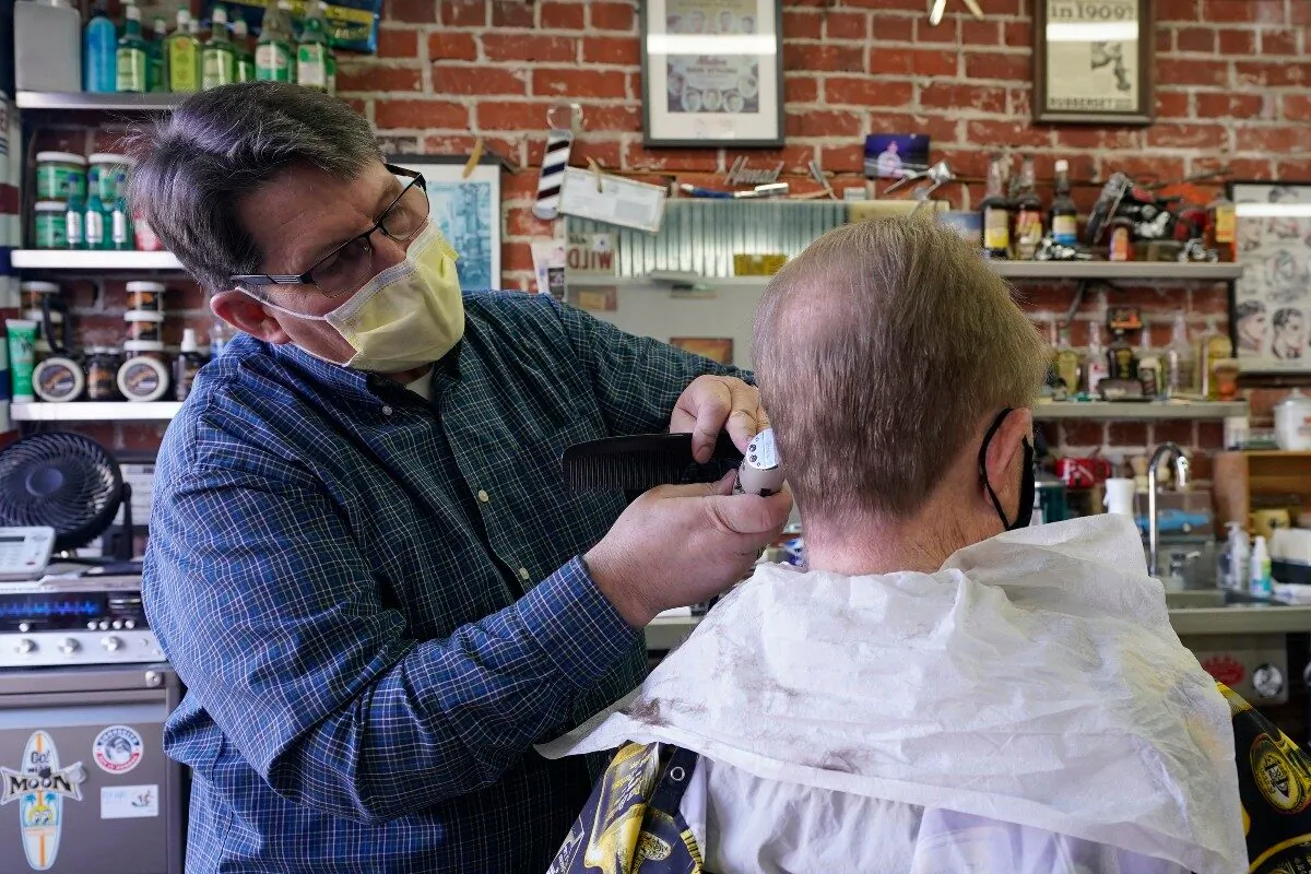 Mike Douglass (L) gives Kent Kjestrom a haircut at East J Barbers in Sacramento, Calif., on Jan. 21, 2021. (Rich Pedroncelli/AP Photo)
