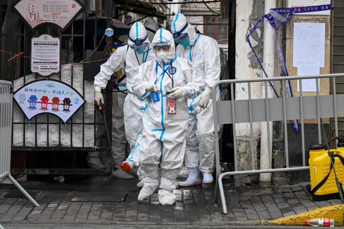 Health workers in protective gear walk out from a blocked off area after spraying disinfectant in Shanghai's Huangpu district on Jan. 27, 2021, after residents were evacuated following the detection of a few cases of COVID-19 coronavirus in the neighborhood. (STR/AFP via Getty Images)