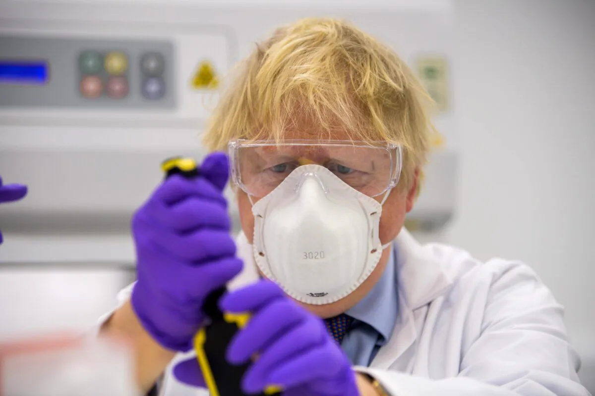 Boris Johnson tries his hand at one of the tests as he visits the French biotechnology laboratory Valneva in Livingston, Scotland, on Jan. 28, 2021. (Wattie Cheung-WPA Pool/Getty Images)