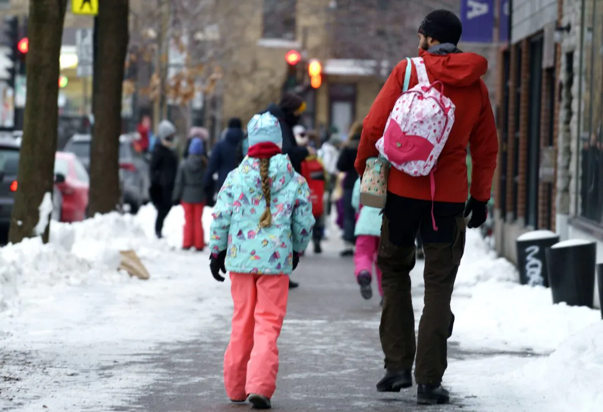 Parents walk their children to school in Montreal on Jan. 11, 2021. (The Canadian Press/Paul Chiasson)