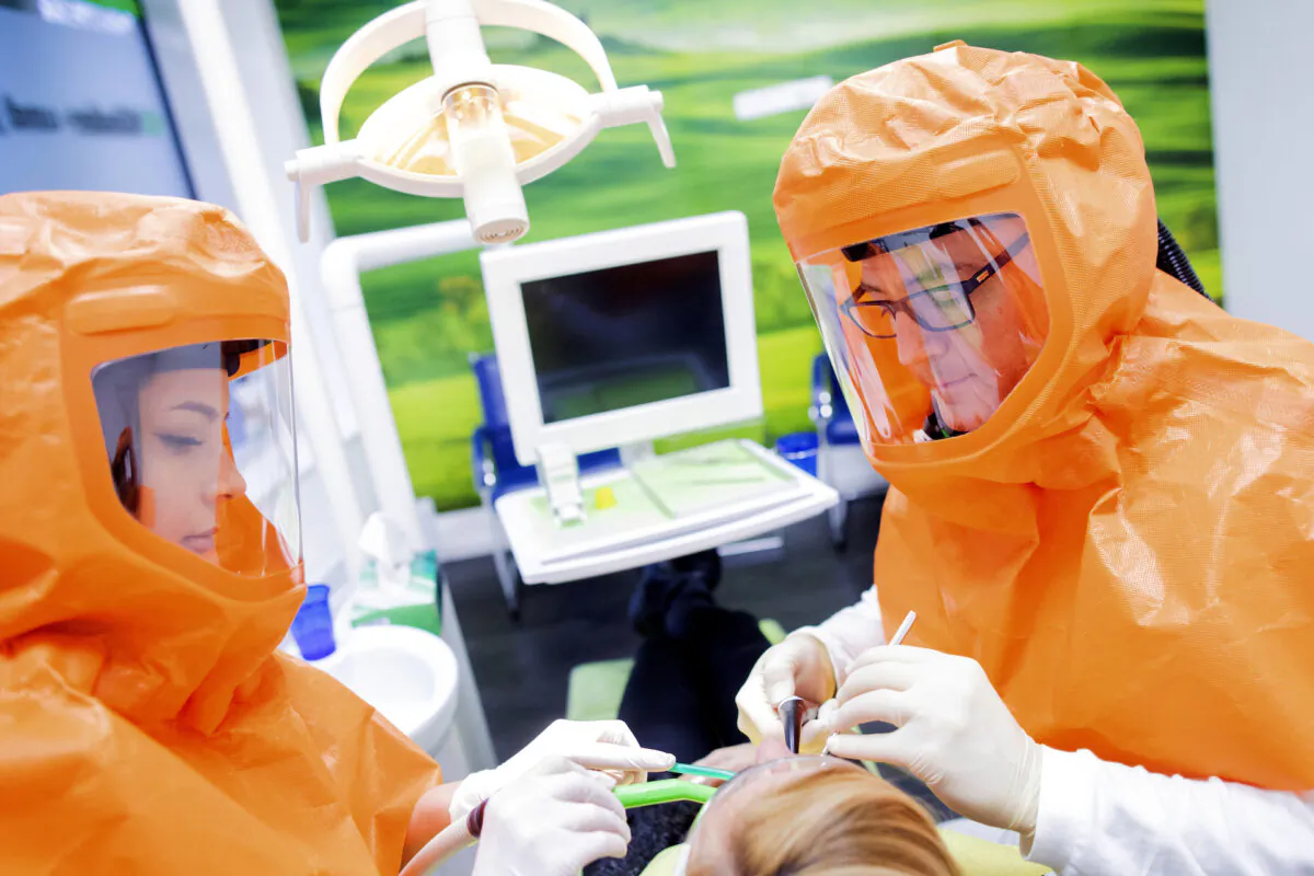 Dentists treat a patient while wearing full protective hoods in Oberhausen, Germany, on Jan. 27, 2021. (Rolf Vennenbernd/dpa via AP)