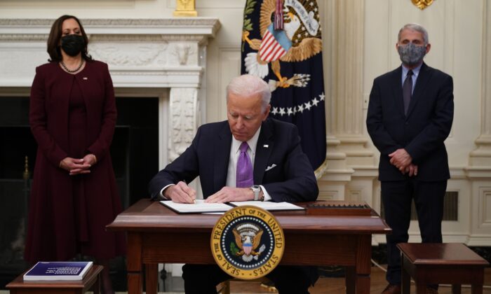 President Joe Biden signs executive orders as Vice President Kamala Harris and Director of NIAID Anthony Fauci look on in the White House in Washington on Jan. 21, 2021. (Mandel Ngan/AFP via Getty Images)