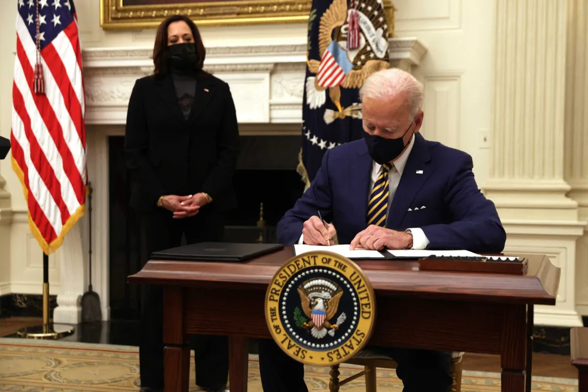 President Joe Biden signs an executive order as Vice President Kamala Harris looks on during an event on economic crisis in the State Dining Room of the White House in Washington Jan. 22, 2021. (Alex Wong/Getty Images)