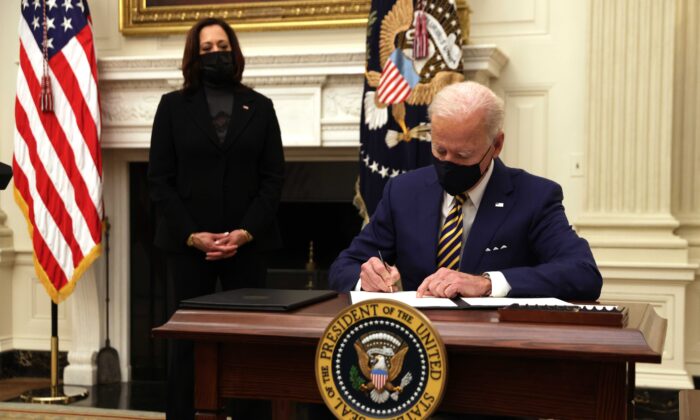 President Joe Biden signs an executive order as Vice President Kamala Harris looks on during an event on economic crisis in the State Dining Room of the White House in Washington Jan. 22, 2021. (Alex Wong/Getty Images)