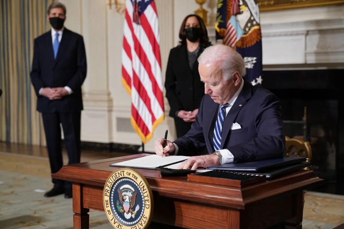 Vice President Kamala Harris (2-L) and special presidential envoy for climate John Kerry (L) watch as President Joe Biden signs several executive orders related to climate change, including one directing a pause on new oil and natural gas leases on public land, in the State Dining Room of the White House in Washington on Jan. 27, 2021. (Mandel Ngan/AFP via Getty Images)