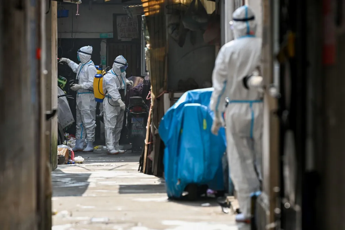 Health workers in protective gear spray disinfectant in a blocked off area in Shanghai's Huangpu district on Jan. 27, 2021, after residents were evacuated following the detection of a few cases of COVID-19 coronavirus in the neighbourhood. (STR/AFP via Getty Images)