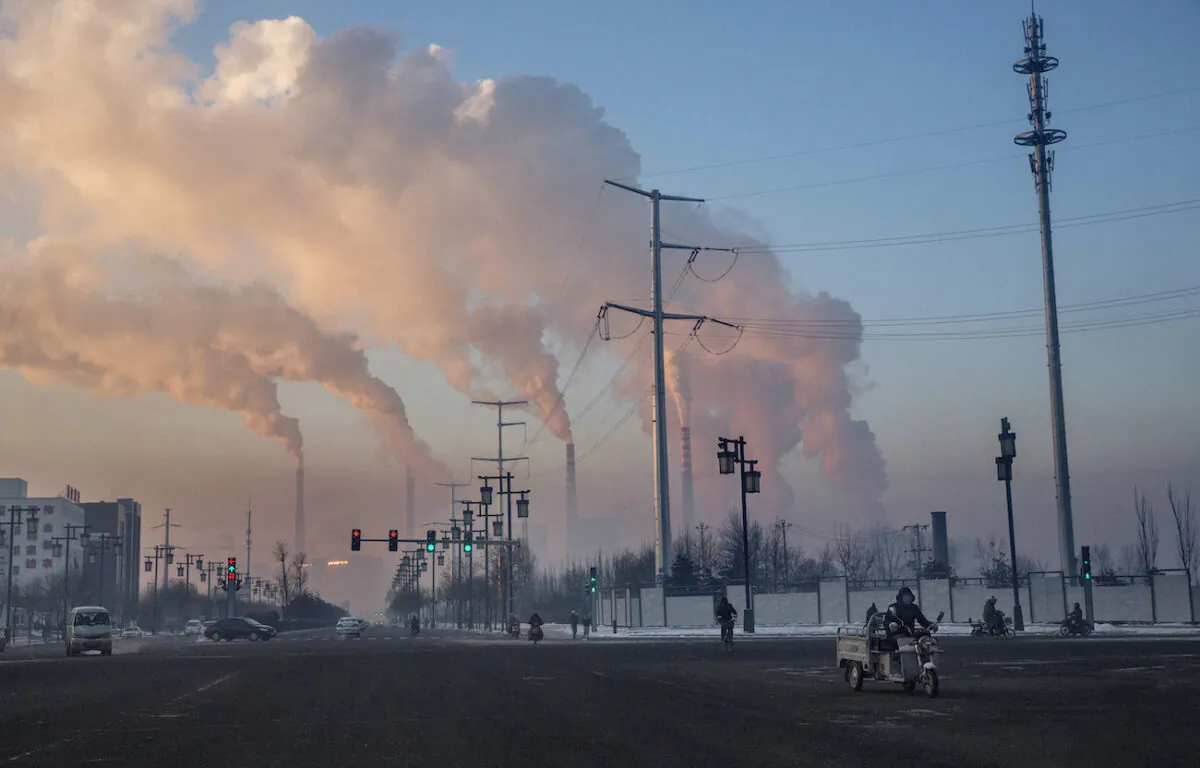 Chinese workers commute as smoke billows from a coal fired power plant in Shanxi, China, on Nov. 25, 2015. (Kevin Frayer/Getty Images)