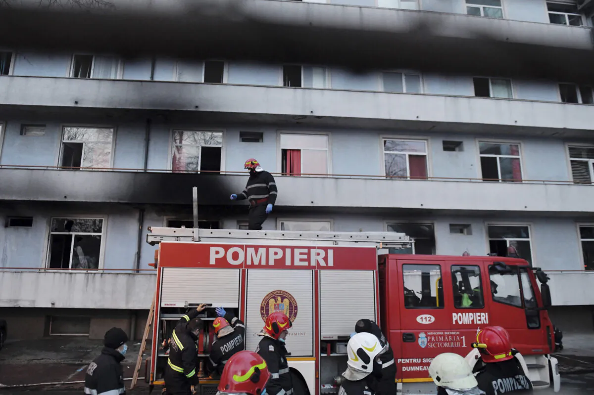 A firefighter stands on top of a fire engine outside a hospital after a fire broke out on the ground floor, Romania, on Jan. 29, 2021. (Andreea Alexandru/AP Photo)