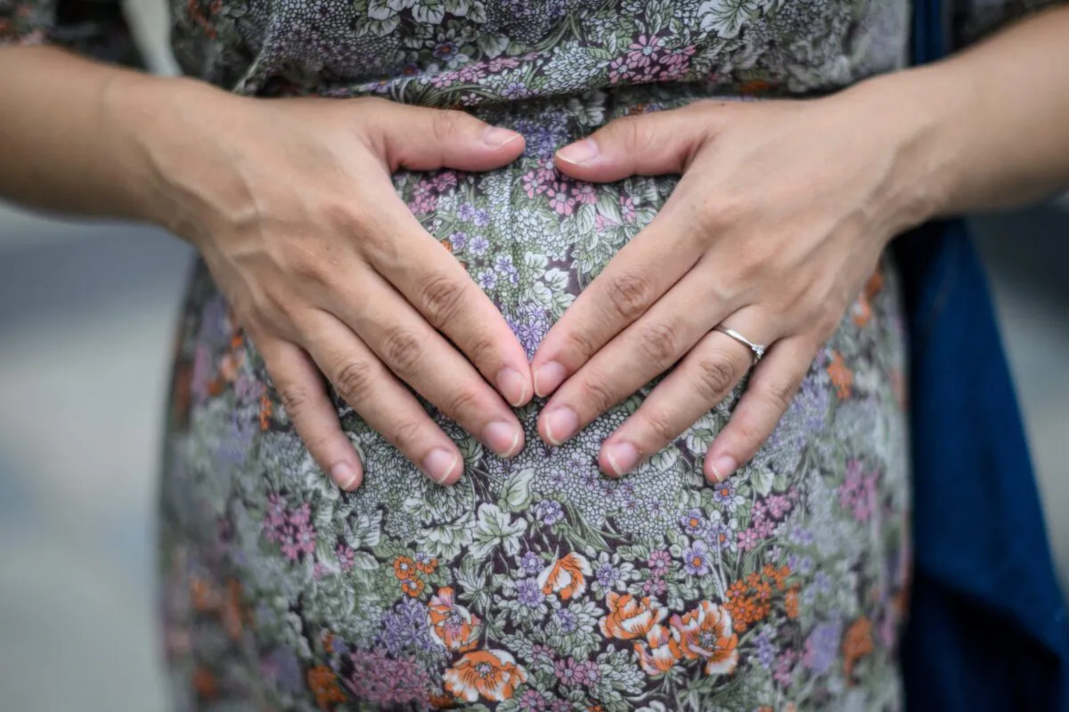 An expectant mother rests her hands upon her baby bump in Hong Kong, on March 31, 2020. (Anthony Wallace/AFP via Getty Images)