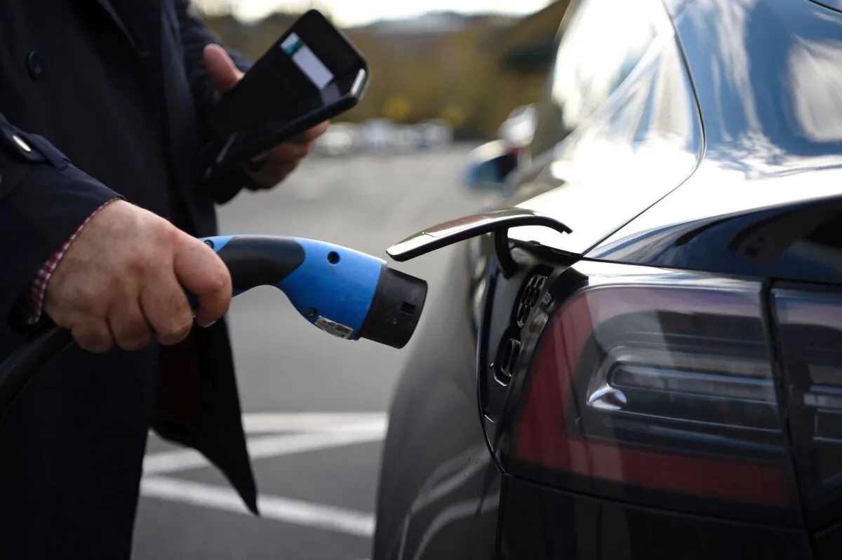 A customer prepares to charge his Tesla electric vehicle (EV) after  parking in a bay for electric vehicles at a supermarket in north London on Nov. 18, 2020. (Daniel Leal-Olivas /AFP via Getty Images)