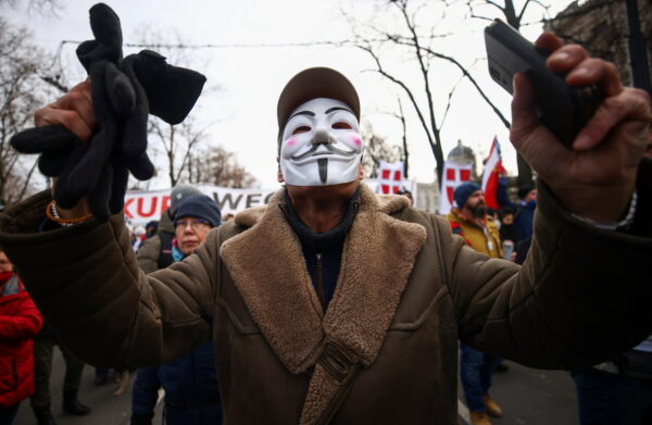 A man wearing a mask gestures during a demonstration