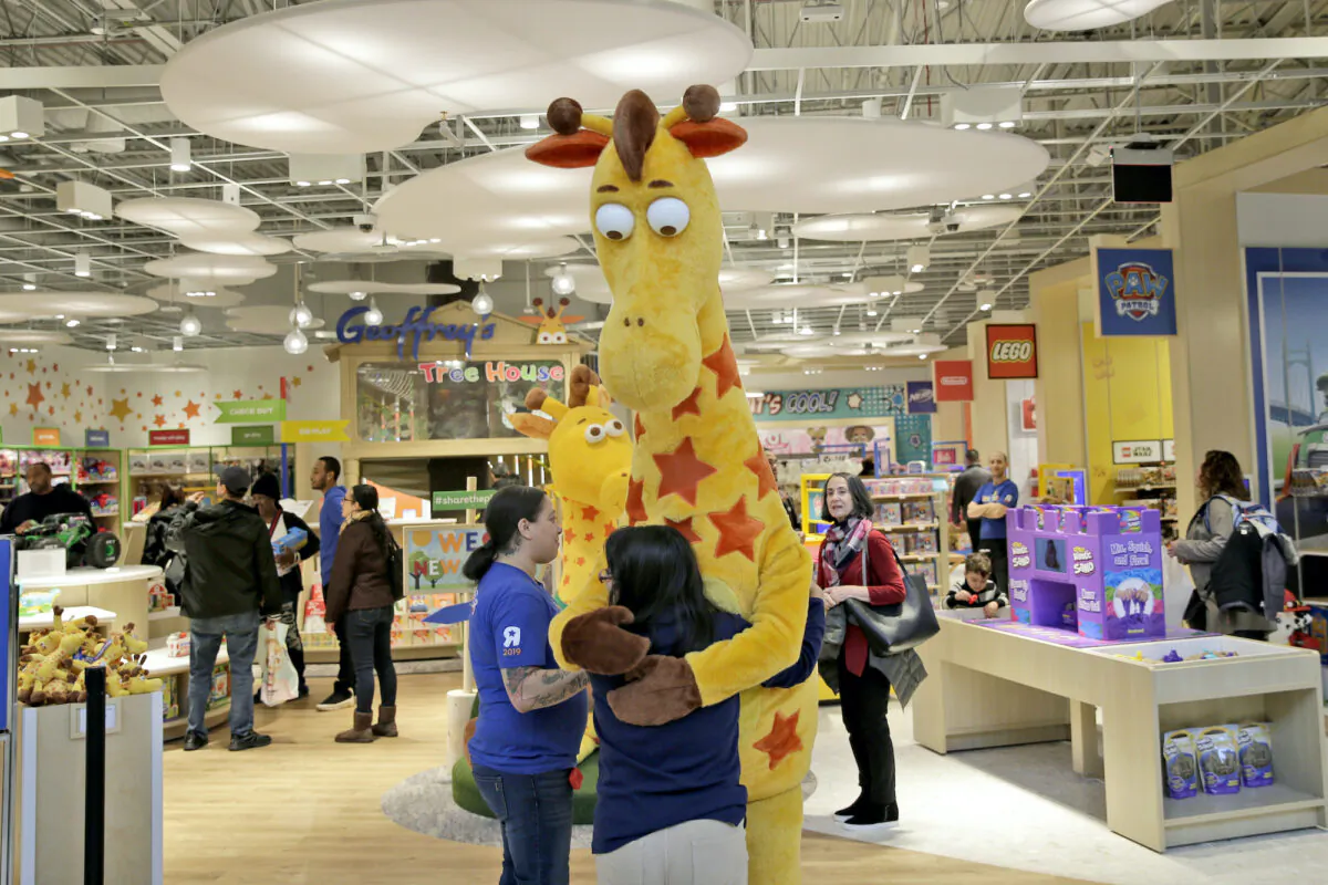 A girl hugs the Toys R Us mascot, Geoffrey, at the new store at a mall in Paramus, NJ, on Dec. 9, 2019. (Seth Wenig/AP Photo)