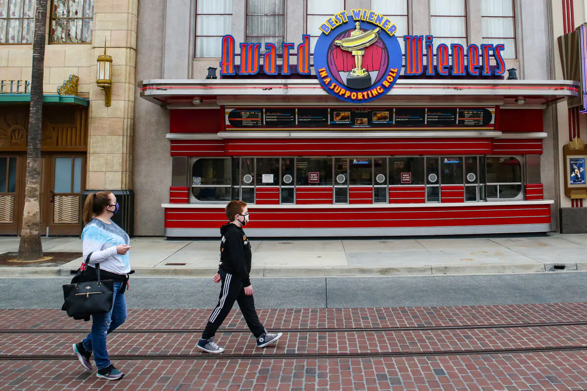 People walk by a closed hot dog shop at Disneyland California Adventure theme park in Anaheim, Calif., on Feb. 1, 2021. (John Fredricks/The Epoch Times)