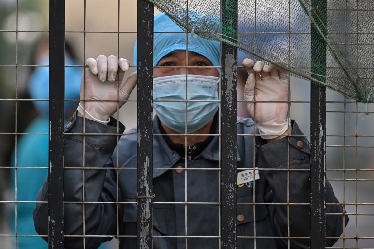 A worker wearing a face mask looks out from an entrance of a hospital toward the Wuhan centre for disease control and prevention in Wuhan, China's central Hubei province on Feb. 1, 2021. (Hector Retamal/AFP via Getty Images)