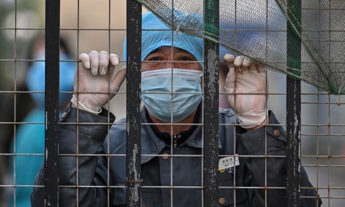 A worker wearing a face mask looks out from an entrance of a hospital toward the Wuhan centre for disease control and prevention in Wuhan, China's central Hubei province on Feb. 1, 2021. (HECTOR RETAMAL/AFP via Getty Images)