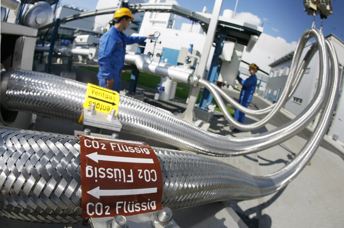 Two employees work on pipes carrying liquid CO2 at the "Schwarze Pumpe" ("Black Pump") power station Vattenfall in Werder, Germany on Sept. 8, 2008. The power station is using Carbon Capture and Storage, or CCS, which captures the greenhouse gases produced when fossil fuels are combusted. (Michael Urban/ DDP/AFP via Getty Images)