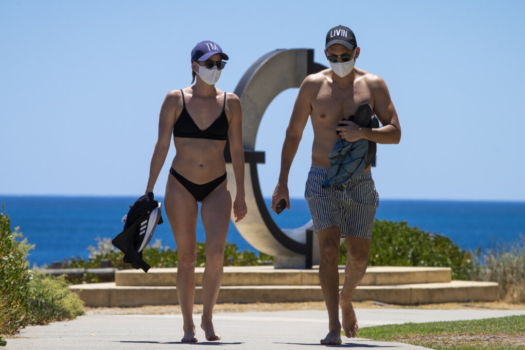 A young couple at Cottesloe Beach wearing mandatory face masks after an hour of recreational exercise is permitted in Perth, Australia on Feb. 1, 2021. (Matt Jelonek/Getty Images)