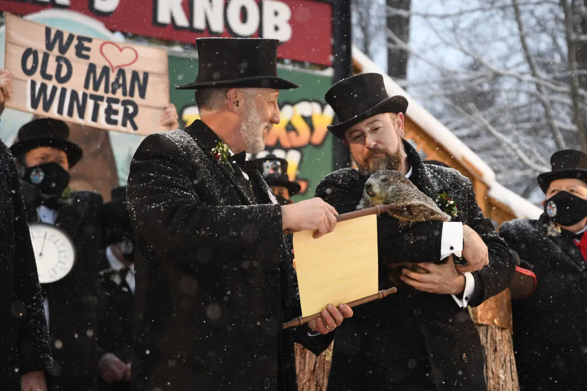 Groundhog Club handler A.J. Dereume holds Punxsutawney Phil, the weather prognosticating groundhog, as Vice President Tom Dunkel reads the scroll during the 135th celebration of Groundhog Day on Gobbler's Knob in Punxsutawney, Pa., on Feb. 2, 2021. (Barry Reeger/AP Photo)