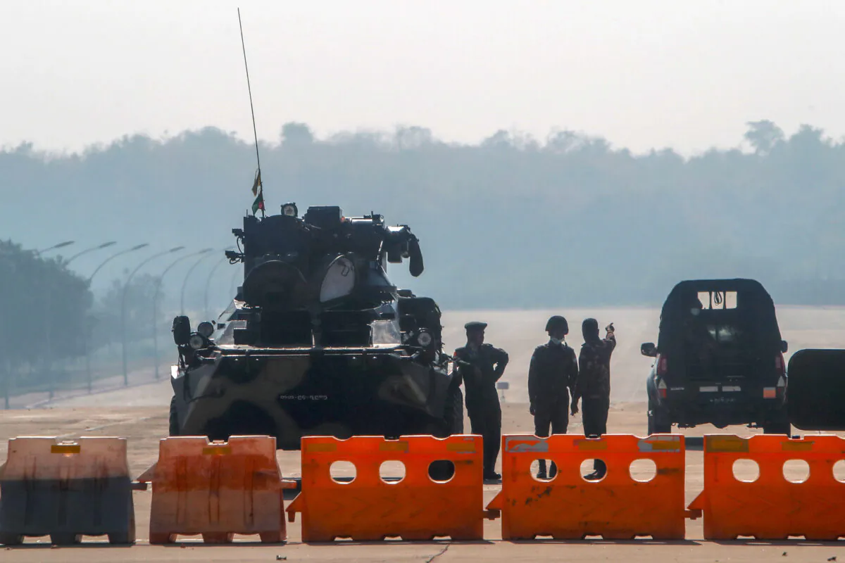 Military members stand guard at a checkpoint manned with an armored vehicle in a road leading to the parliament building Naypyitaw, Burma, on Feb. 1, 2021. (AP Photo)