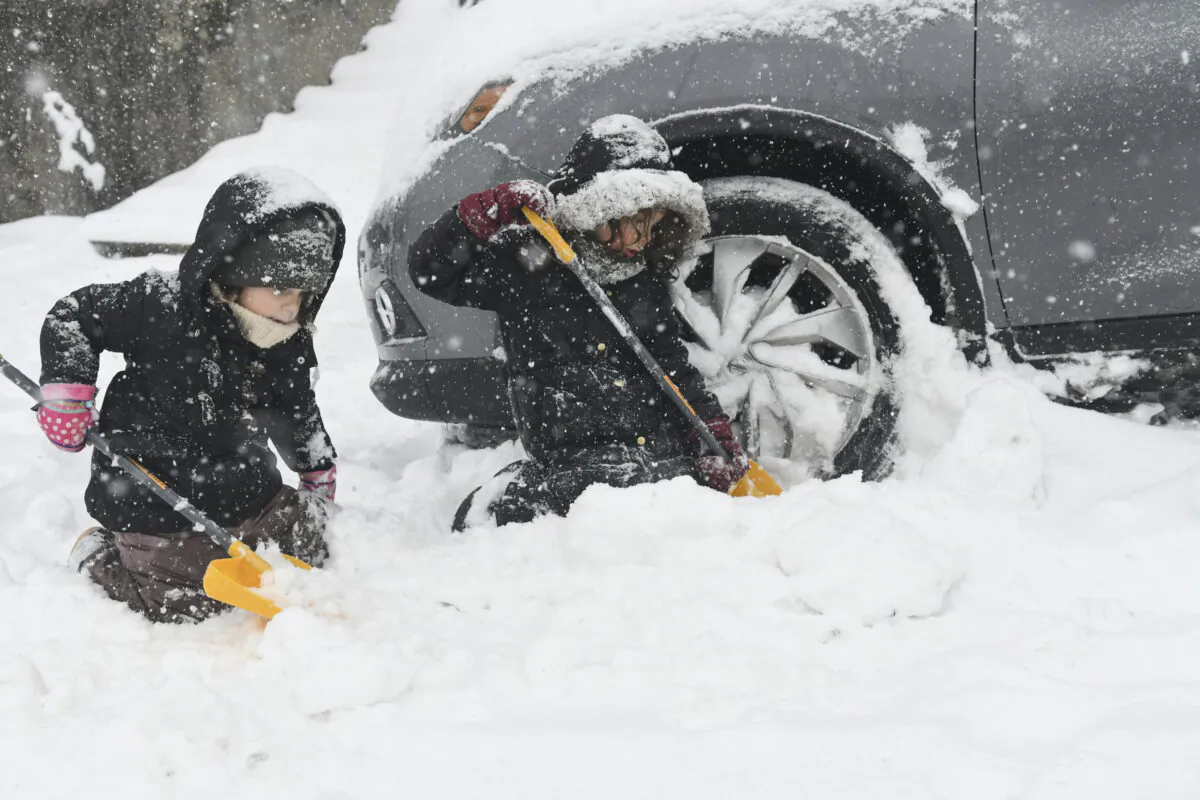 Perrin Sue Peters (L) and her sister Harlow Peters, of Pottsville, Pa., help their mother Aubrey shovel out her car in Pottsville, Pa., on Feb. 1, 2021. (Jacqueline Dormer/Republican-Herald via AP)