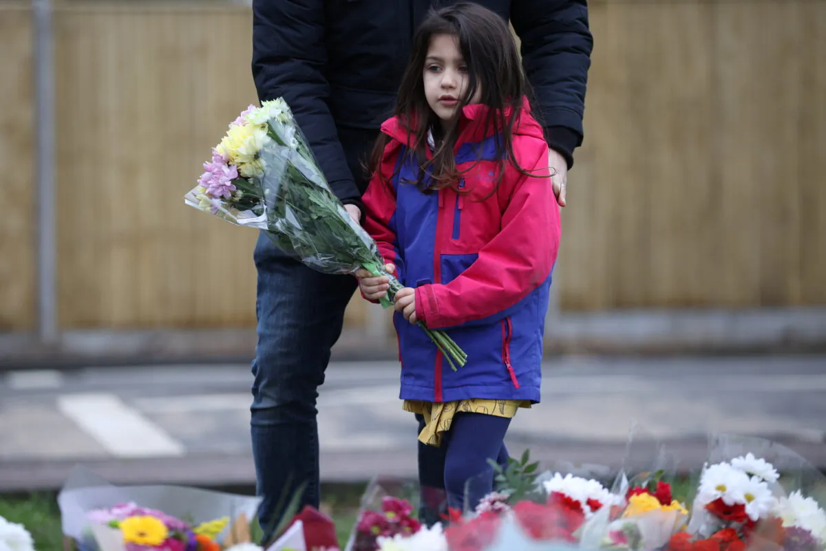 A girl lays flowers near the residence of Captain Sir Tom Moore, after his family announced that the centenarian fundraiser died, in Marston Moretaine near Milton Keynes, Britain, on Feb. 3, 2021. (Hannah McKay/Reuters)