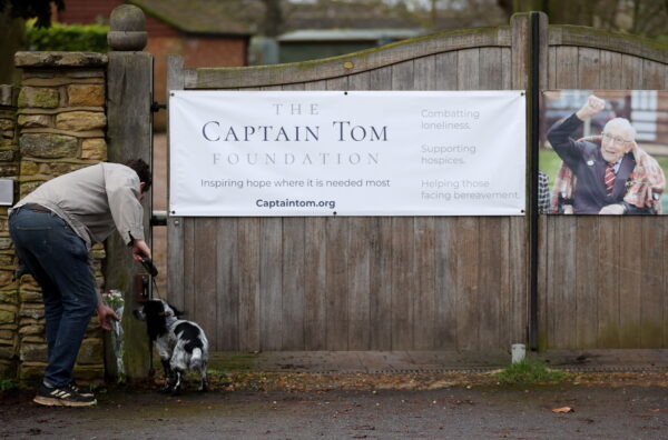 A person lays flowers at the gate to the residence of Captain Sir Tom Moore
