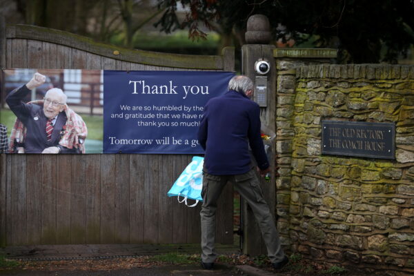 A person lays flowers at the gate to the residence of Captain Sir Tom Moore