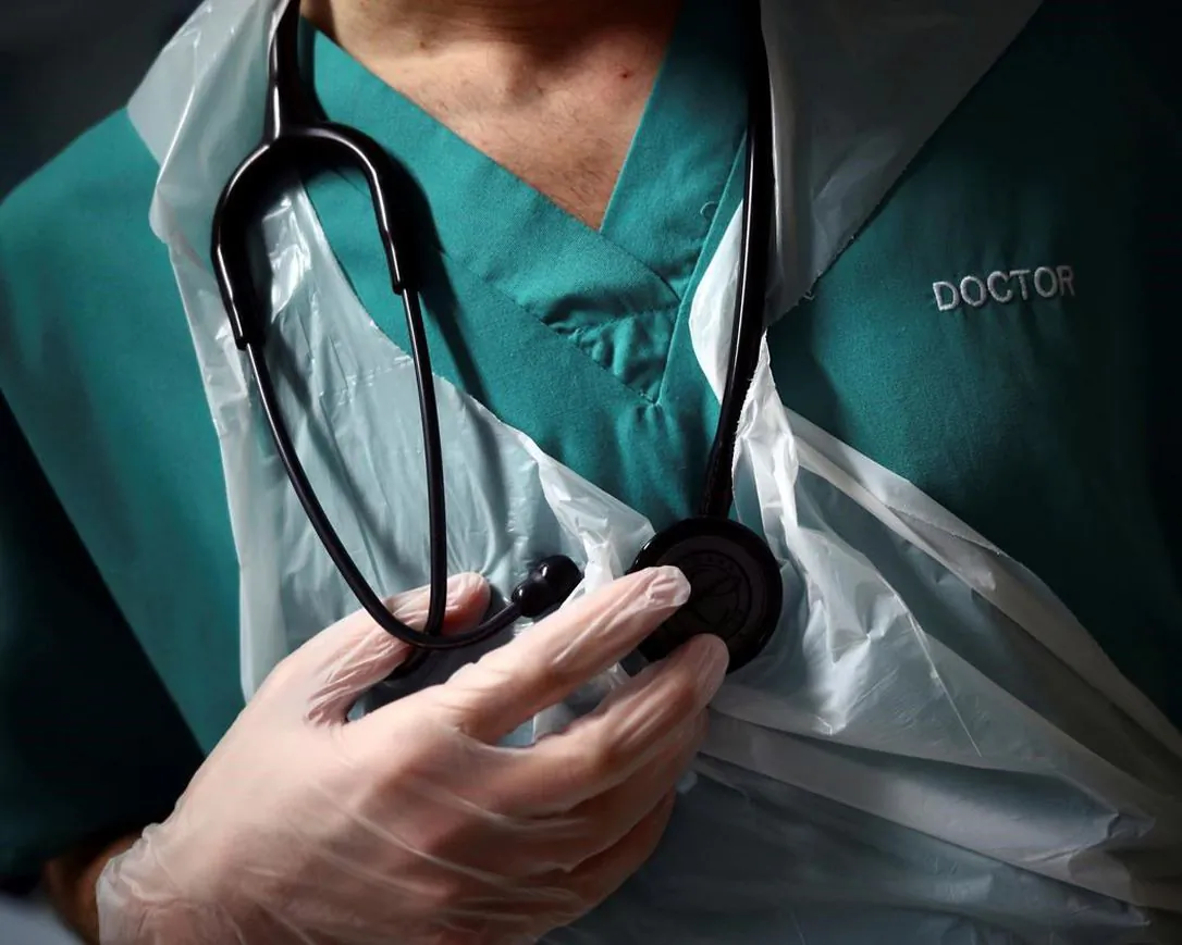 A junior doctor holds his stethoscope during a patient visit at the Royal Blackburn Teaching Hospital, in Blackburn, England, amid the COVID-19 pandemic on May 14, 2020. A francophone doctor accused of misconduct by Ontario's medical regulator has lost his bid to have his case heard by a French-speaking disciplinary panel. (Hannah McKay/The Canadian Press/Pool Photo via AP)